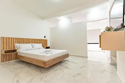 a bedroom with a bed with white walls and marble floors at Hotel Loft 72 in Medellín