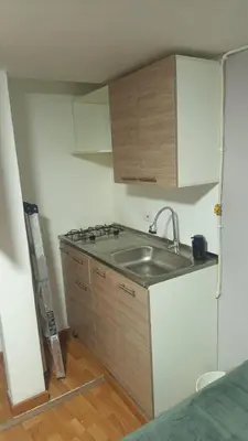 a small kitchen with a sink and wooden cabinets at Apartaestudio muy central entre zonas rosas in Manizales