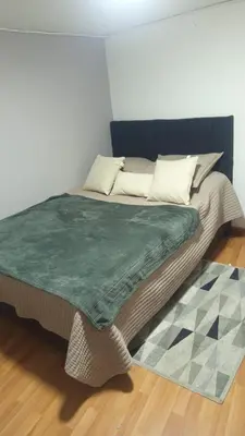 a bed with a green blanket on top of it at Apartaestudio muy central entre zonas rosas in Manizales