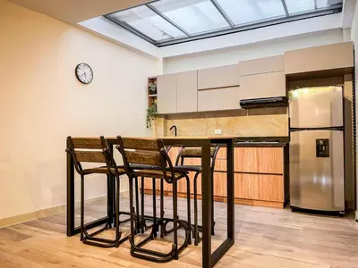 a kitchen with a counter with stools and a refrigerator at Vive Medellin apartamento in Envigado
