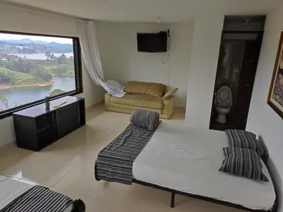 a bedroom with a bed and a couch and a large window at Finca Villa Lake in Horizonte