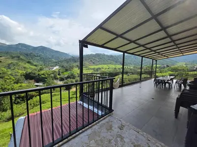 a balcony with tables and chairs and mountains in the background at FINCA DE RECREO y DESCANSO in El Bosque