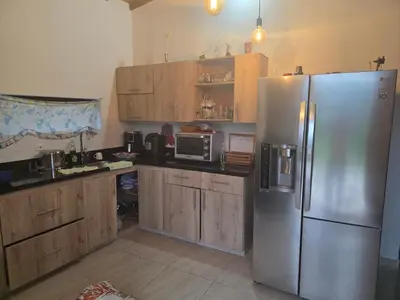 a kitchen with a stainless steel refrigerator and wooden cabinets at FINCA DE RECREO y DESCANSO in El Bosque