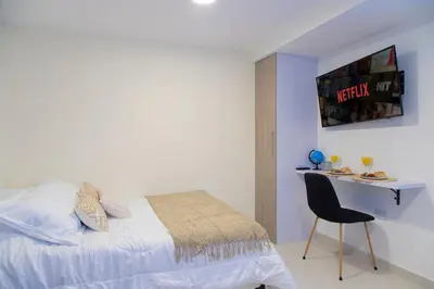 a bedroom with a bed and a desk with a chair at Sencia Apartamentos Boutique in Medellín