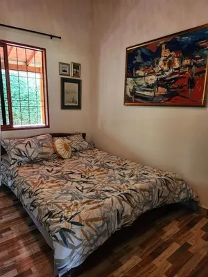 a bed in a bedroom with a painting on the wall at Eco-paradise in coffee heartland in Marulanda