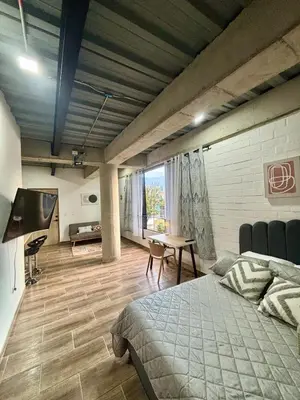 a bedroom with a bed and a table in a room at Industrial Loft near Poblado, Medellín in Medellín
