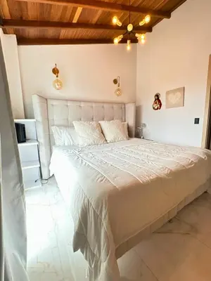 a white bed in a bedroom with a wooden ceiling at Casa Bosques La Ceja in La Ceja