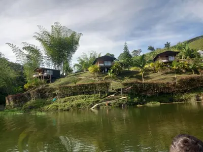 a group of houses on a hill next to a river at Cabañas con vista al Embalse in La Pradera