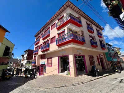 a pink building with red and blue balconies on a street at Apto full Ubicación Plazoleta Zocalos Plaza Ppal in Guatapé