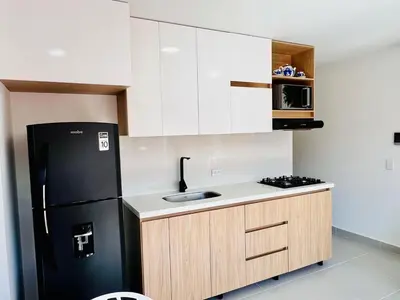a kitchen with a black refrigerator and white cabinets at Apto full Ubicación Plazoleta Zocalos Plaza Ppal in Guatapé