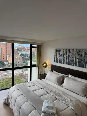 a bedroom with a large bed with a large window at Reposso Laureles in Medellín
