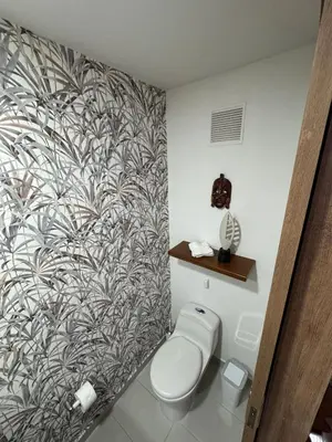 a bathroom with a toilet with a leafy wallpaper at Reposso Laureles in Medellín