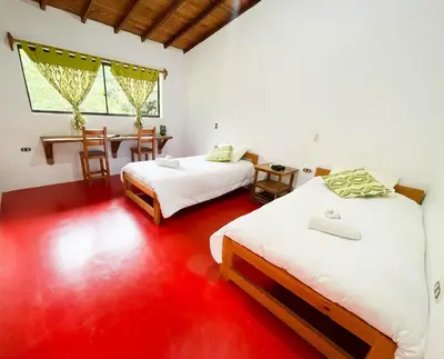 two beds in a room with a red floor at Las Tangaras Reserve