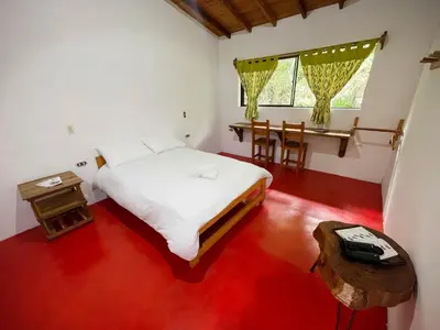 a bedroom with a bed and a table and a window at Las Tangaras Reserve
