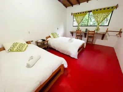 two beds in a room with a red floor at Las Tangaras Reserve