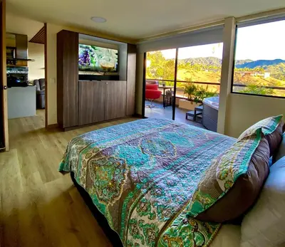 a bedroom with a bed and a large window at San Telmo Apartment with Jacuzzy in Guatapé