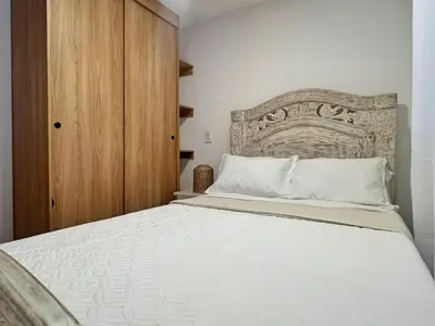a bedroom with a large bed with a wooden headboard at Acogedor en parque principal Guatape con Jacuzzi in Guatapé