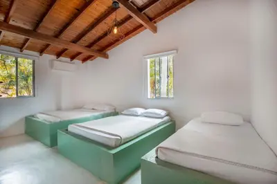two beds in a room with two windows at Fina Hotel La Morenita in Santa Fe de Antioquia