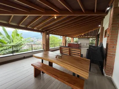 a deck with a wooden table and chairs on a balcony at AMAZING EL POBLADO VIEWs-MODERN VILLA in Envigado