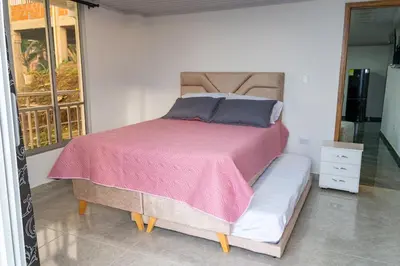 a bedroom with a bed with a pink comforter at Casa con vista a la montaña en Manizales in Manizales