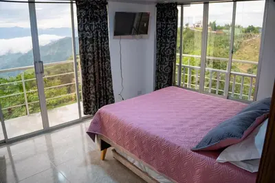 a bedroom with a bed and a large window at Casa con vista a la montaña en Manizales in Manizales