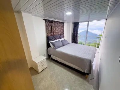 a bedroom with a bed and a large window at Casa con vista a la montaña en Manizales in Manizales