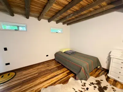 a bedroom with a bed and a wooden floor at Wooden House in Rionegro