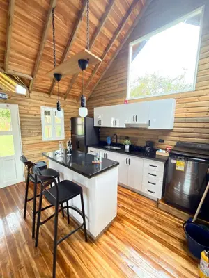 a kitchen with white cabinets and a island with stools at Wooden House in Rionegro