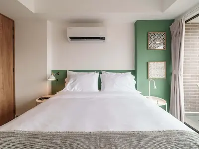 a bedroom with a large white bed with a green wall at Engaging Loft with Balcony in Laureles in Medellín