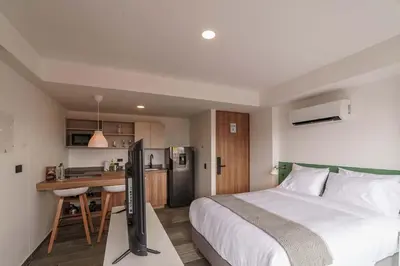 a bedroom with a bed and a desk with a television at Engaging Loft with Balcony in Laureles in Medellín