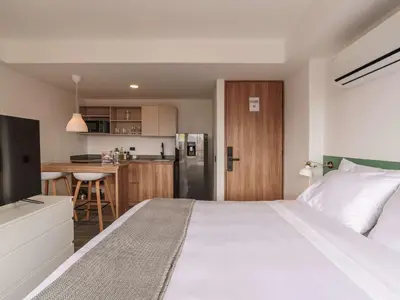 a bedroom with a large white bed and a kitchen at Engaging Loft with Balcony in Laureles in Medellín