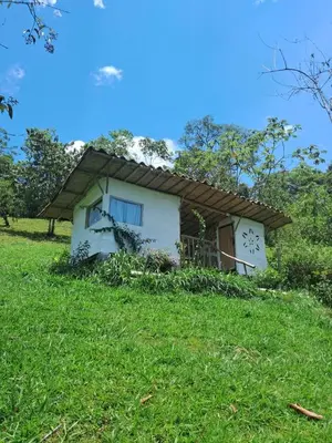 a small white house on a grassy hill at Familia Verde Eco Hostal in San Carlos