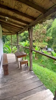 a wooden porch with a picnic table and benches at Familia Verde Eco Hostal in San Carlos