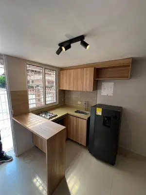 a kitchen with a black refrigerator and wooden cabinets at Ideal apartment, view, park and key location in Medellín