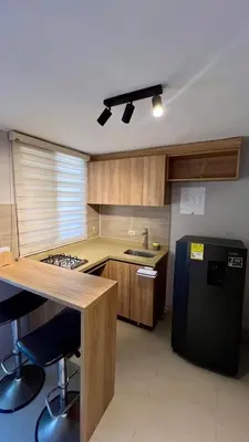 a kitchen with a black refrigerator and wooden cabinets at Ideal apartment, view, park and key location in Medellín