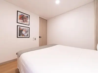 a bedroom with a white bed and two pictures on the wall at NOK Panoramic 3 BR in Laureles Medellin in Medellín