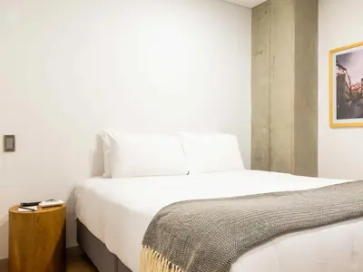 a bedroom with a white bed and a wooden night stand at NOK Panoramic 3 BR with terrace in Laureles Medellin in Medellín
