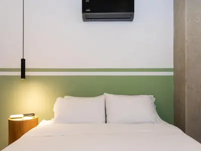a bed with two pillows and a television above it at NOK Cozy 3 BR with Balcony in Laureles Medellin in Medellín