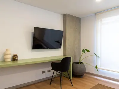 a room with a chair and a television on a wall at NOK Cozy 3 BR with Balcony in Laureles Medellin in Medellín