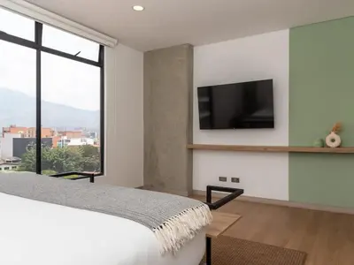 a bedroom with a bed and a tv on a wall at NOK Charming 3BR in Laureles Medellin in Medellín