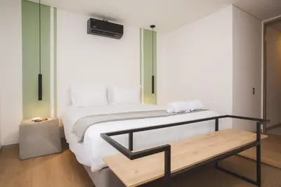 a bedroom with a bed and a wooden bench at NOK Amazing with Balcony 3 BR in Laureles Medellin in Medellín