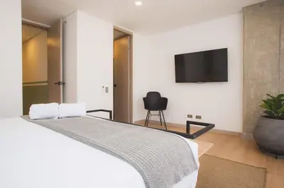 a bedroom with a bed with a tv on the wall at NOK Amazing with Balcony 3 BR in Laureles Medellin in Medellín