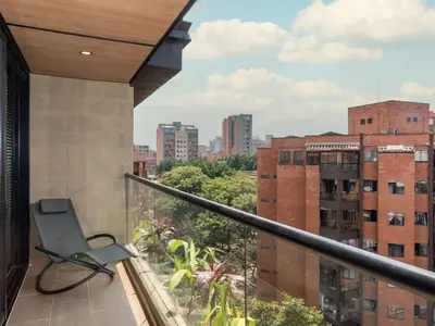 a chair on a balcony with a view of a city at NOK Lovely 3 BR with Balcony in Laureles Medellin in Medellín