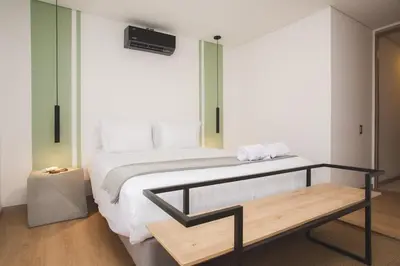 a bedroom with a large bed and a bench at NOK Cool 3 BR With Balcony in Laureles Medellin in Medellín