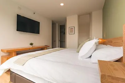 a bedroom with a large white bed with a flat screen tv at Mountain Views, AC, King Bed, Fast WiFi in Medellín