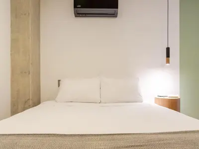 a bedroom with a white bed with a tv on the wall at NOK Bright 3BR with terrace in Laureles Medellin in Medellín