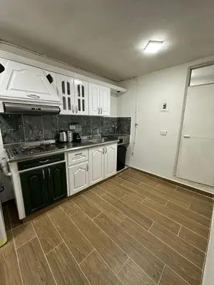 a kitchen with white cabinets and a wooden floor at Hermoso apartamento en la milagrosa in Medellín