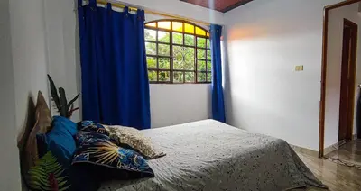 a bedroom with a bed with blue curtains and a window at Alcoba independiente en nuestro hogar santa Elena encantada in Santa Elena