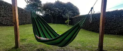 a green hammock hanging from two poles in a yard at Alcoba independiente en nuestro hogar santa Elena encantada in Santa Elena