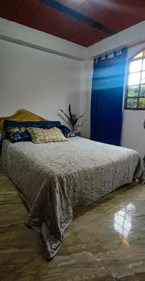 a bed in a bedroom with a blue curtain at Alcoba independiente en nuestro hogar santa Elena encantada in Santa Elena